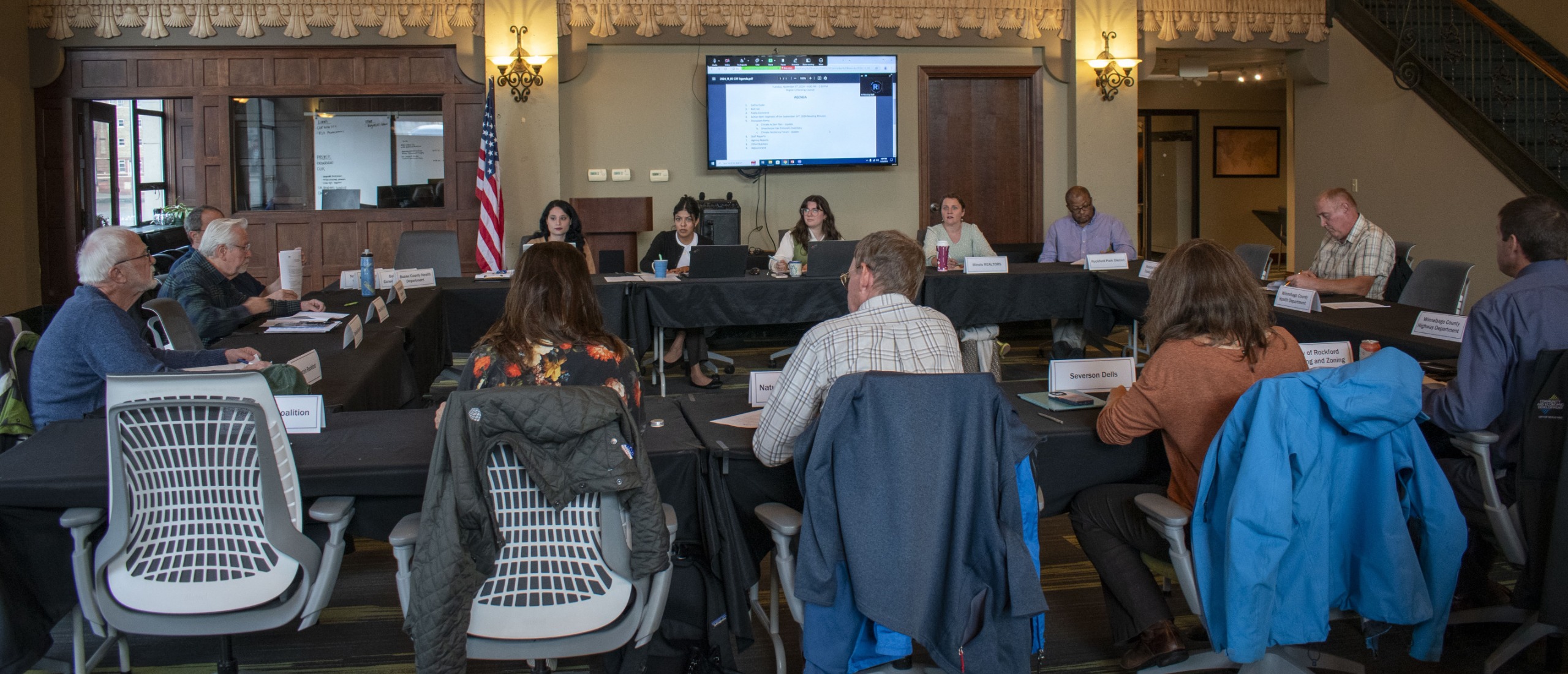 Meeting of the Climate Resiliency Forum. Image depicts a room full of people sat around a table with a presentation screen in the background.